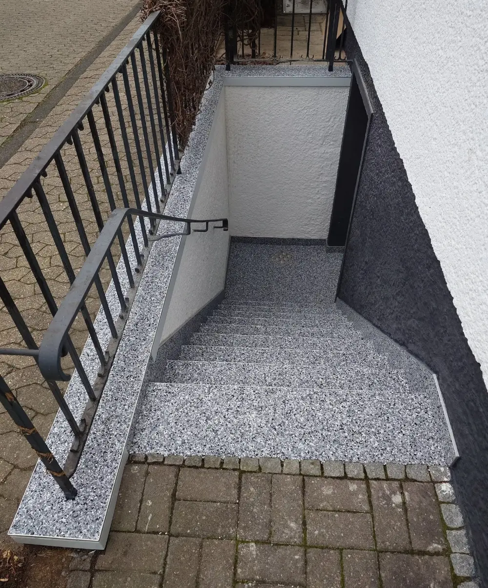 Sanierte Kellertreppe mit grauem Steinteppich und abgedichteten Anschlüssen