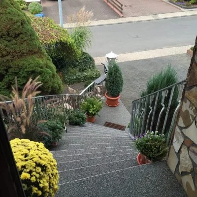 Sanierte Außentreppe mit grauem Steinteppich und Metallgeländer