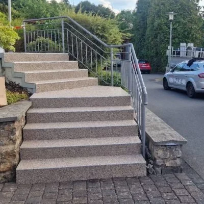 Sanierte Außentreppe mit hellem Steinteppich und Metallgeländer