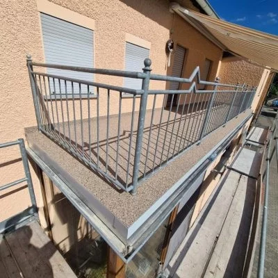 Balkon mit grauem Steinteppich und umlaufendem Metallgeländer