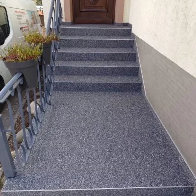 Sanierte Eingangstreppe mit grauem Steinteppich und Podest